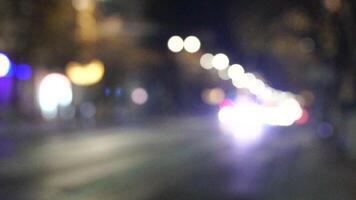 desenfocado coche luces en un noche ciudad calle. abstracción. borroso antecedentes. multicolor círculos de ligero. lento movimiento fuera de atención noche calle puntos de vista de el ciudad carreteras. video