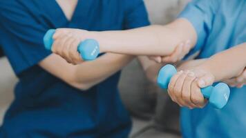 Lycklig senior kvinna håller på med övning på Hem med fysioterapeut. gammal pensionerad lady håller på med stretching vapen på Hem med de hjälp av en personlig tränare under en rehabilitering session. video