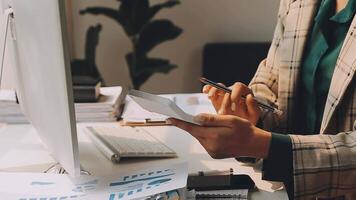 Mujer de negocios que usa la calculadora para hacer finanzas matemáticas en un escritorio de madera en la oficina y el fondo de trabajo empresarial, impuestos, contabilidad, estadísticas y concepto de investigación analítica video