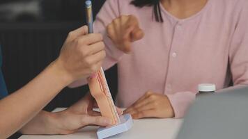 Aziatisch vrouw dokter vervelend gezicht masker is tonen een rectaal model- en uitleggen naar ouderling senior Mens geduldig in ziekenhuis video