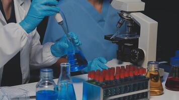 Young scientists conducting research investigations in a medical laboratory, a researcher in the foreground is using a microscope video