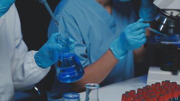 Young scientists conducting research investigations in a medical laboratory, a researcher in the foreground is using a microscope video