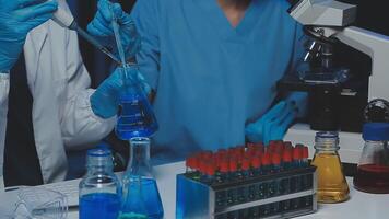 Young scientists conducting research investigations in a medical laboratory, a researcher in the foreground is using a microscope video