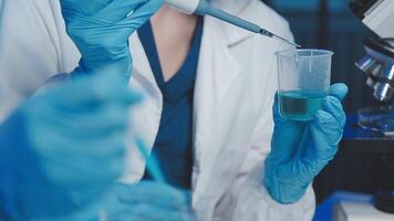 Young scientists conducting research investigations in a medical laboratory, a researcher in the foreground is using a microscope video