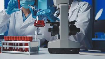 Young scientists conducting research investigations in a medical laboratory, a researcher in the foreground is using a microscope video