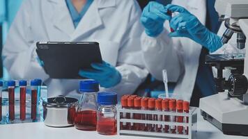 Young scientists conducting research investigations in a medical laboratory, a researcher in the foreground is using a microscope video