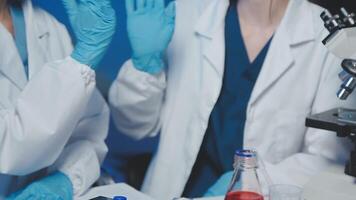 Young scientists conducting research investigations in a medical laboratory, a researcher in the foreground is using a microscope video