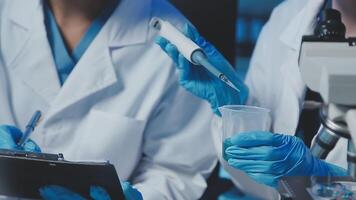 Young scientists conducting research investigations in a medical laboratory, a researcher in the foreground is using a microscope video