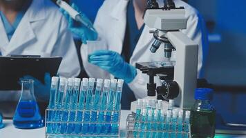 Young scientists conducting research investigations in a medical laboratory, a researcher in the foreground is using a microscope video