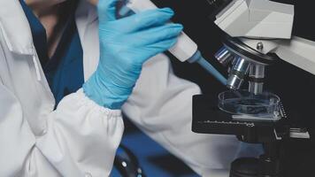 Young scientists conducting research investigations in a medical laboratory, a researcher in the foreground is using a microscope video