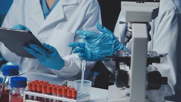 Young scientists conducting research investigations in a medical laboratory, a researcher in the foreground is using a microscope video