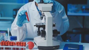 Young scientists conducting research investigations in a medical laboratory, a researcher in the foreground is using a microscope video