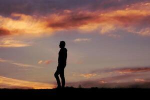 hombre silueta en el campo y puesta de sol antecedentes foto