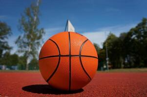 Orange basketball against the blue cloudy sky photo