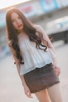 Beautiful Asian woman poses in fashion style, white shirt, jeans skirt. photo