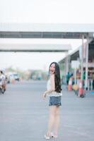 Beautiful Asian woman poses in fashion style, white shirt, jeans skirt. photo