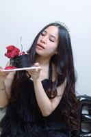 Beautiful woman wearing a black dress and chocolate cake in the concept of birthday photo