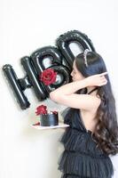 Beautiful woman wearing a black dress and chocolate cake in the concept of birthday photo