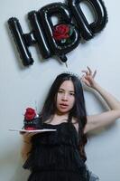 Beautiful woman wearing a black dress and chocolate cake in the concept of birthday photo