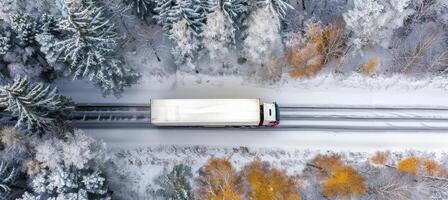 ai generado aéreo zumbido ver de coche y camión conducción en nieve cubierto la carretera en blanco invierno bosque paisaje foto