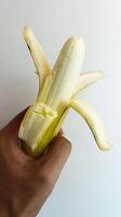 mano participación un amarillo plátano en un blanco antecedentes foto