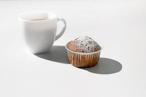 Mañana desayuno con magdalena taza de té y mollete en un blanco mesa. foto