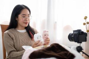 A cheerful young Asian female content creator showing her cute handmade plushie to the camera. photo