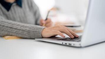 A close-up image of a woman is working on her laptop in a modern office, typing on the keyboard. photo