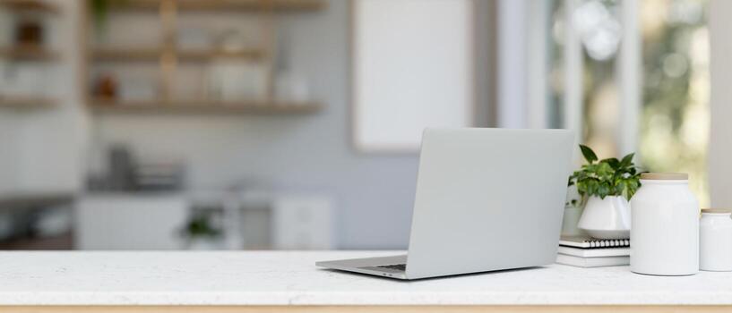 A back view image of a laptop computer and decor on a white table in a modern and clean office. photo
