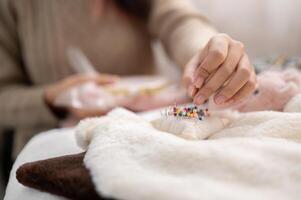 A close-up image of a woman pinning a pin on a pin cushion, stitching cloth, crafting handmade items. photo