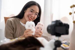 A cheerful young Asian female content creator showing her cute handmade plushie to the camera. photo