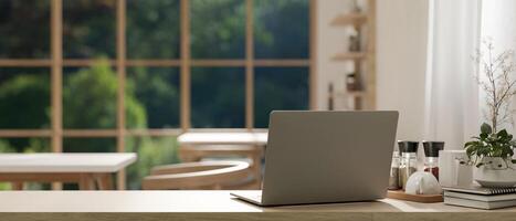 A back view image of a laptop on a wooden table in a cosy Scandinavian coffee shop co-working space photo