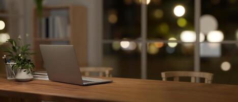 A back view image of a laptop on a dining table in a comfortable, minimalist dining room at night. photo