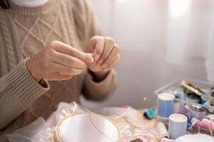 un de cerca imagen de un mujer insertando un aguja, enhebrar un de coser aguja, de coser a hogar. foto