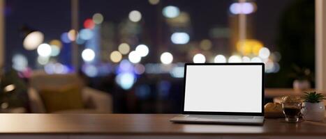 Workspace at night, a laptop mockup on a desk in a contemporary private office room on a skyscraper. photo