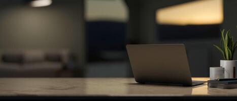 A back view image of a laptop computer and decor on a table in a contemporary living room at night. photo