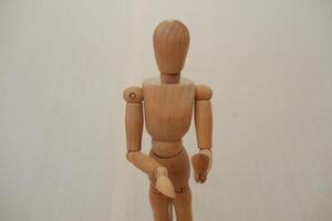 Wooden mannequin standing on a wooden background. Selective focus. photo