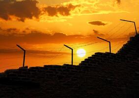 prisión pared y eléctrico vallas a puesta de sol. libertad temática foto