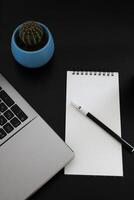 Blank notebook with pen are on top of wood office desk table with a cup of coffee and office supplies, top view. photo