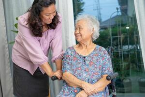 Caregiver help Asian senior woman on wheelchair with love at home. photo