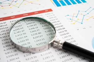 Magnifying glass on spreadsheet and graph paper. Financial development, Banking Account, Statistic, Investment Analytic research data economy, Business. photo