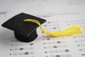 Graduation gap hat and pencil on answer sheet background, Education study testing learning teach concept. photo