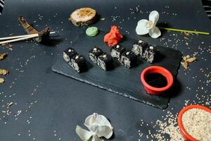 Black Plate With Sushi Alongside Rice Bowl photo