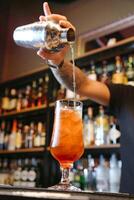 Bartender Pouring a Cocktail Into a Stemmed Glass photo