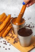 Person Dips Churros Into Cup of Chocolate photo