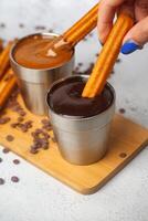 Person Dipping Churros Into a Cup of Chocolate photo