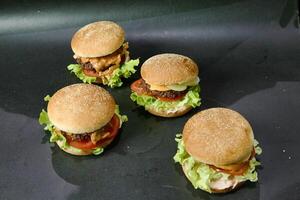 Four Hamburgers With Lettuce and Tomato on a Black Surface photo