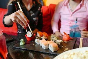 dos mujer disfrutando Sushi juntos a un mesa foto