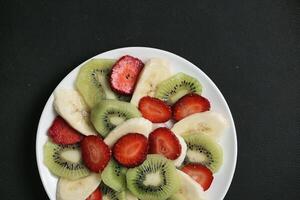 blanco plato con rebanado kiwi y fresas foto