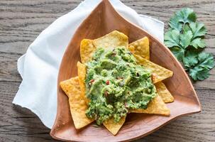 Guacamole with tortilla chips on the wooden background photo